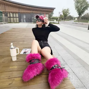 Pink Y2K faux fur snow boots with punk studded straps worn by a model in a trendy outdoor setting
