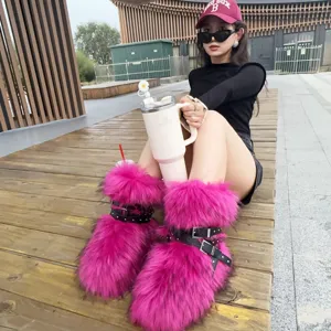 Close-up of pink faux fur snow boots with black buckle straps and rivets in Y2K style