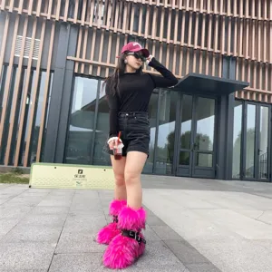 Hot pink Y2K style faux fur snow boots with punk buckles on a model outdoors.