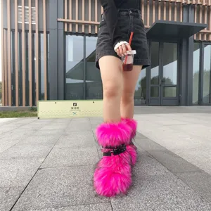 Street style shot of neon pink faux fur snow boots with black punk straps and metal rings