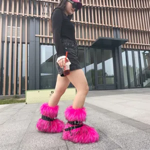 Vibrant pink faux fur platform boots with studded buckle straps in a stylish street setting.
