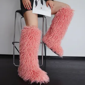 Detailopname van roze harige knielaarzen van imitatiebont gedragen door een model op een kruk