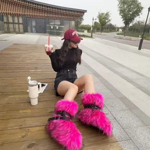 Detail of pink faux fur Y2K boots with black straps and studs shown on a model outdoors