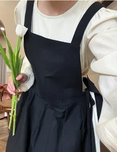 Vista dettagliata di un elegante grembiule di cotone nero plissettato da donna con spalline