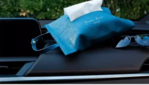 Dettaglio di un sacchetto per fazzoletti in pelle blu sul cruscotto dell'auto.