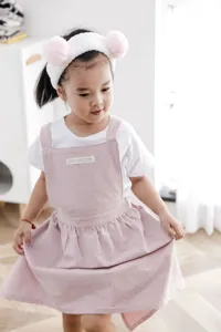 Adorable niña pequeña con un delantal infantil de algodón rosa resistente a manchas
