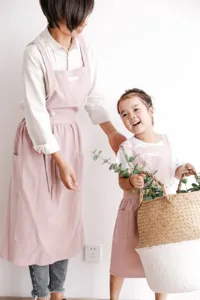 Madre e hija con delantales de algodón rosa a juego para cocinar o hacer manualidades