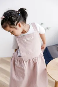 Vista detallada de un delantal minimalista de algodón rosa para niños con etiqueta