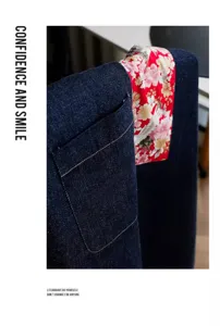 Primer plano de un delantal de mezclilla oscura con bolsillo rojo con estampado floral de grullas