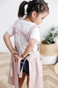 Vista posterior detallada de un delantal infantil de algodón rosa con cintas ajustables.