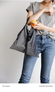 Modella con borsa da pranzo in velluto grigio con ricamo Live Simply dorato elegante