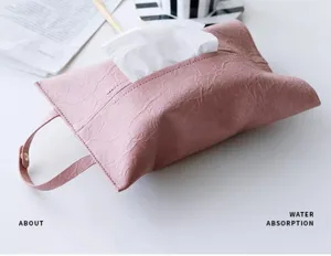 Primo piano di un astuccio per fazzoletti in pelle rosa con cinturino su un tavolo bianco