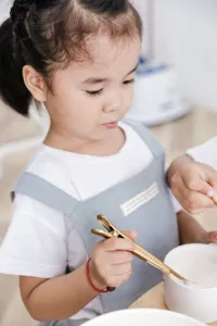 Detalle de un delantal infantil de algodón minimalista en color gris azulado claro.