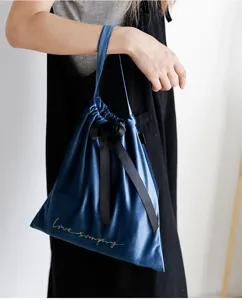 Dettaglio di una borsa da pranzo in velluto blu con fiocco nero e ricamo dorato