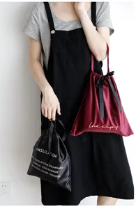 Modella che tiene eleganti borse da pranzo in velluto bordeaux e raso nero con fiocchi