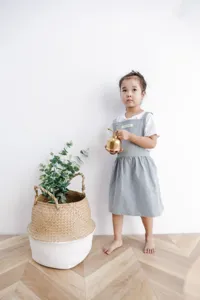 Niña pequeña con un delantal de algodón gris minimalista para cocina o arte