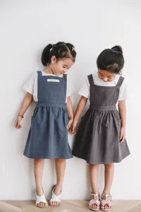 Dos niñas con delantales de algodón de estilo japonés minimalista en azul y gris oscuro