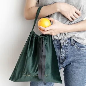 Borsa da pranzo minimalista in velluto verde smeraldo con ricamo dorato tenuta da un modello