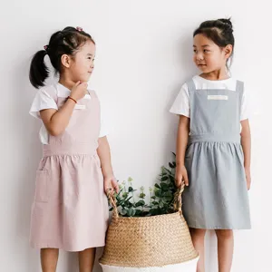Dos niñas pequeñas con delantales de algodón de estilo japonés en color rosa y gris