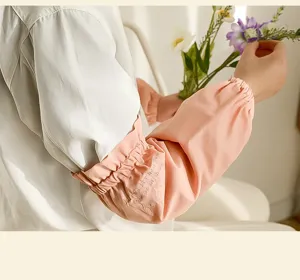 Primo piano di coprimaniche in cotone rosa con eleganti ricami bianchi sui polsini.