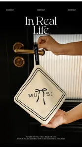 Close-up of a soft cream-colored hand towel with embroidered bow design and hanging strap