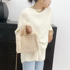 Detalle de un mini bolso tote de piel sintética beige con cadena dorada llevado por modelo