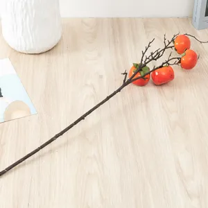 Artificial persimmon fruit branch detail shot, realistic orange fake berries for home decor.