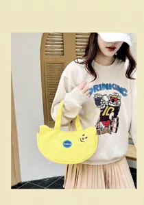 Asiatisches Model mit einer niedlichen gelben Bananen-Stofftasche mit Comic-Stickerei