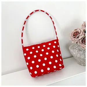 Elegante bolso de nailon rojo con lunares blancos en un estante blanco minimalista