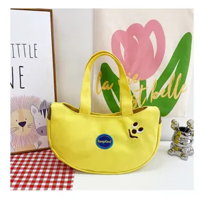 Nahaufnahme einer gelben Bananen-Canvas-Handtasche mit lustiger Cartoon-Gesicht-Stickerei