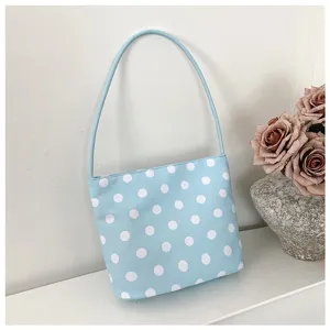 Bolso de hombro de nailon azul claro con lunares blancos junto a elegantes rosas secas