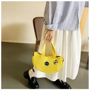 Nahaufnahme eines Models mit einer gelben Bananen-Stofftasche und süßer Stickerei