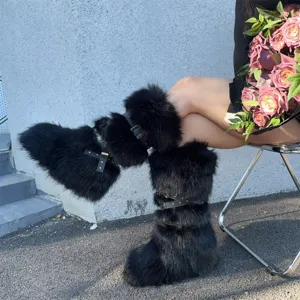 Close-up of stylish Y2K black faux fur boots featuring punk rivet straps on model legs
