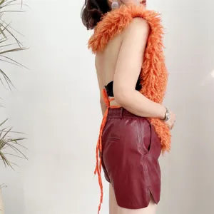 Gedetailleerd zijaanzicht van oranje faux Mongoolse bont top met open rug