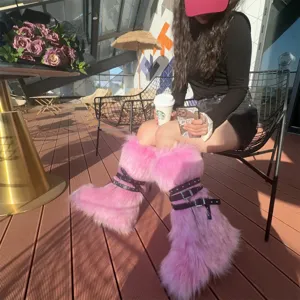 Lifestyle view of pink Y2K faux fur boots with black buckle straps and studs.