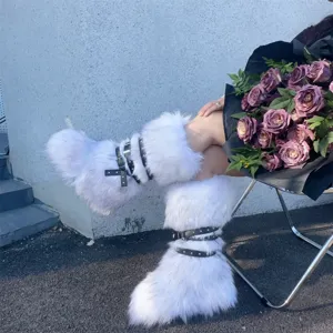 Close-up of stylish white Y2K punk faux fur boots featuring black studded leather straps