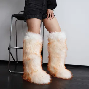 Close-up detail of fluffy Y2K faux fur knee-high snow boots in vibrant white and orange