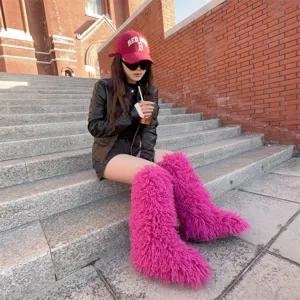 Trendy roze harige kniehoge laarzen van imitatiebont gedragen door een fotomodel.