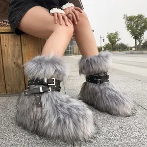 Close-up of Y2K style grey faux fur snow boots with black buckled leather straps and studs.
