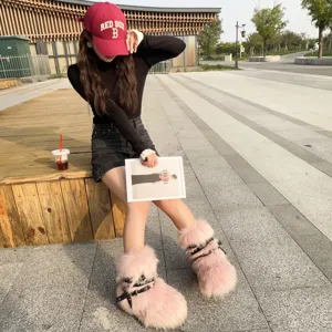 Pink faux fur Y2K punk style snow boots featuring black buckle straps with silver rivets