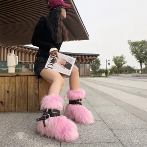 Close-up detail of pink faux fur snow boots featuring black studded buckle straps and punk style