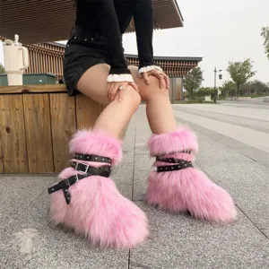Close-up of pink faux fur Y2K snow boots with black punk buckles and silver rivets.