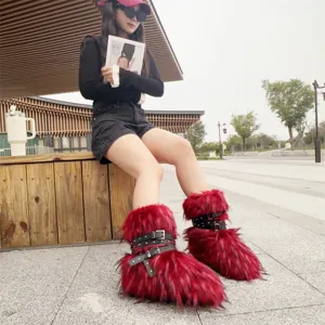 Full view of red faux fur Y2K punk snow boots with studded buckle straps outdoors