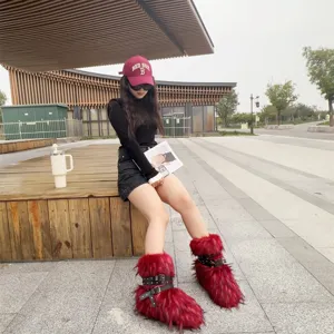 Detail of Y2K red faux fur snow boots with punk buckles and rivets on an outdoor model.