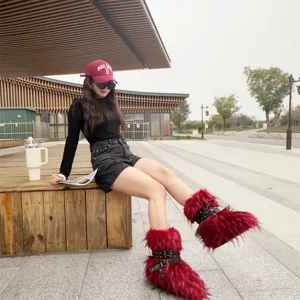 Detailed view of red Y2K faux fur boots with black rivet buckle straps worn by a model