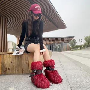 Y2K style red faux fur snow boots with punk rivet straps worn by model in outdoor scene