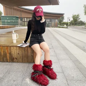 Red faux fur Y2K punk snow boots with black rivet buckle straps worn outdoors