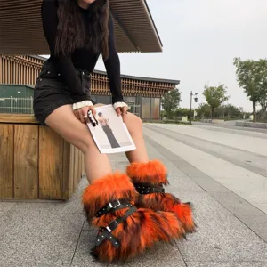 Detail view of orange faux fur Y2K boots with black buckle straps and silver studs