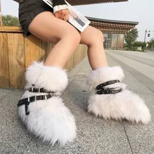 Close-up of stylish white faux fur snow boots with punk-style studded black straps