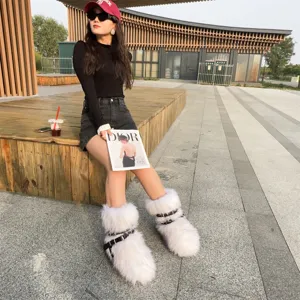 Outdoor view of white faux fur snow boots featuring punk rivets and leather straps